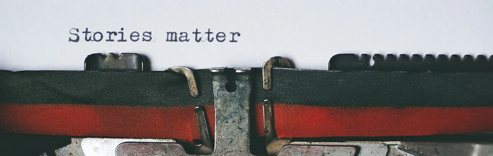 A close up image of an old typewriter showing the ribbon and mechanism. What was typed out reads "stories matter". Our category of Cool Stories found at Ads4Dads.com