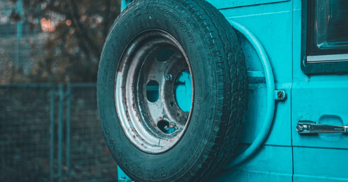 A spare tire on the back of an old, light blue VW bus. Learn about the importance of your spare tire and tips to take care of it in this article.