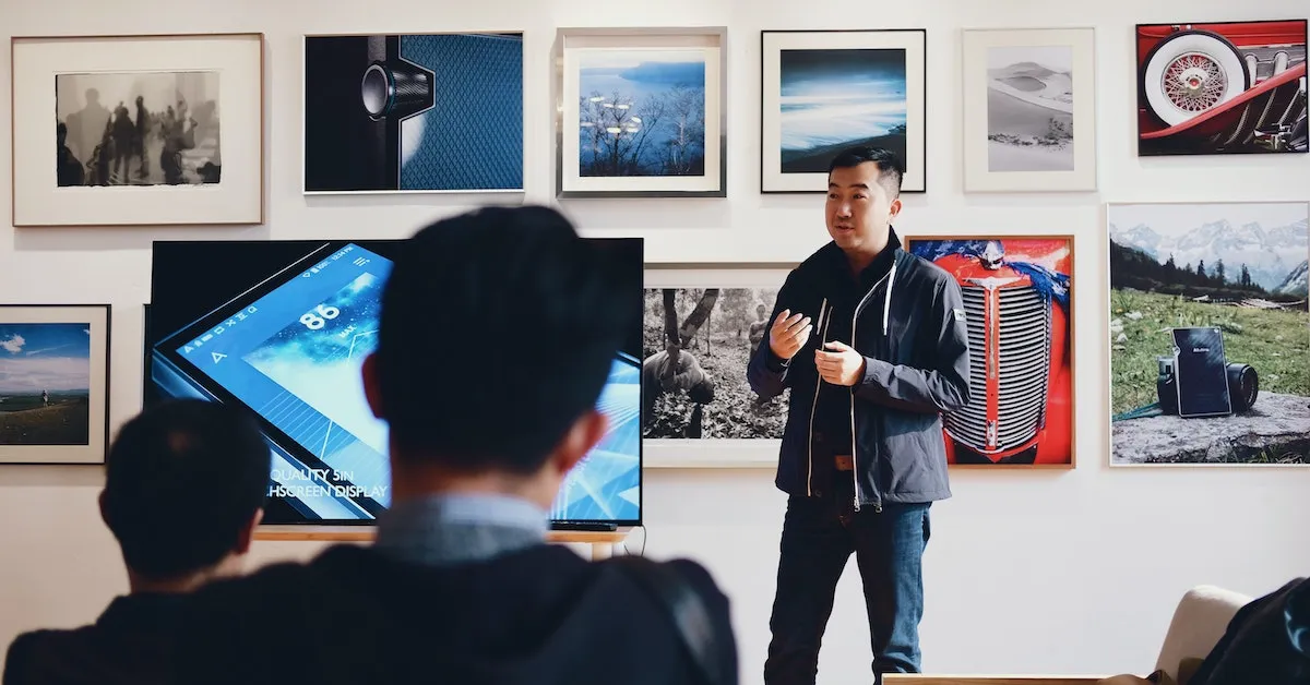 A man leading a public speaking event at an art exhibit. Learn how to have the skills of an excellent public speaker.