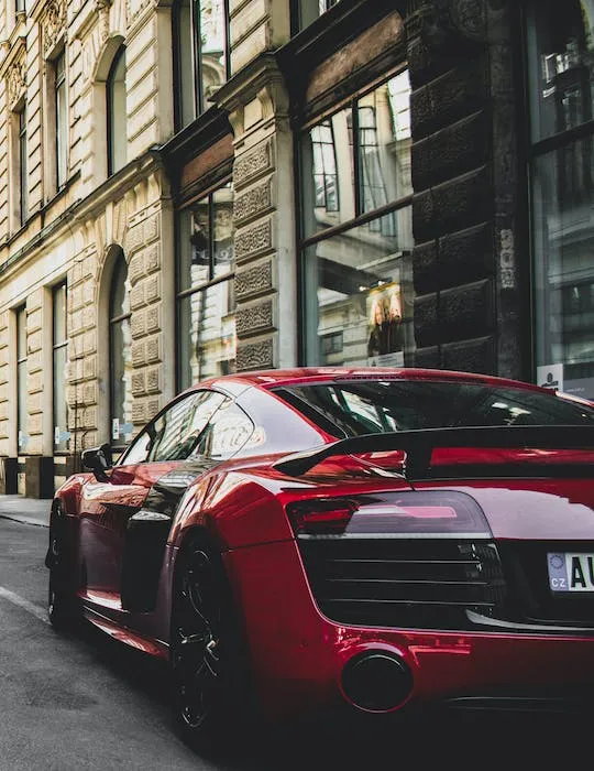 A beautiful dark red Audi R8 parked on the street of a downtown city in Europe. Find it here at Ads4Dads.com