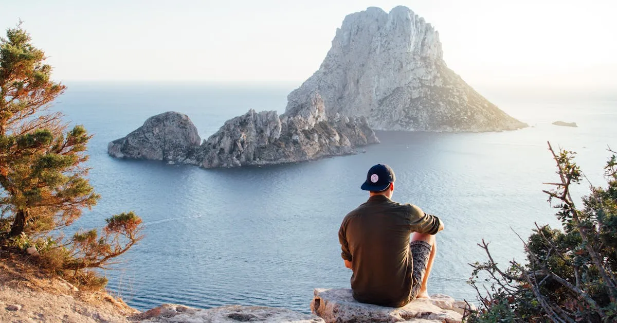 A man sitting by himself overlooking a beautiful view of the ocean with rocky cliffs in the distance. Learn tips to understanding men.