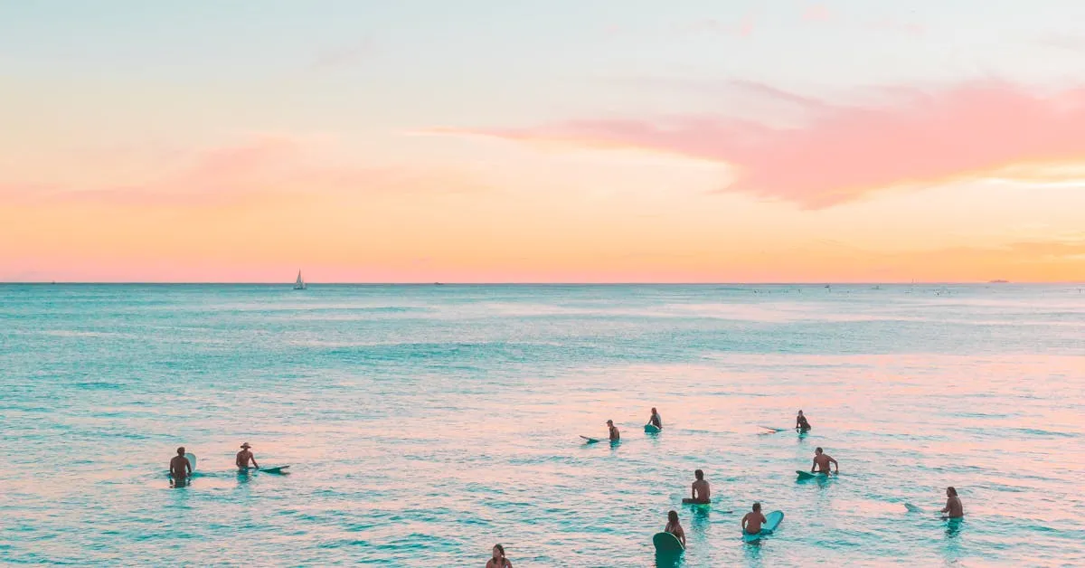 A beautiful sunset on the ocean with surfers waiting for the next wave. Learn more about us!