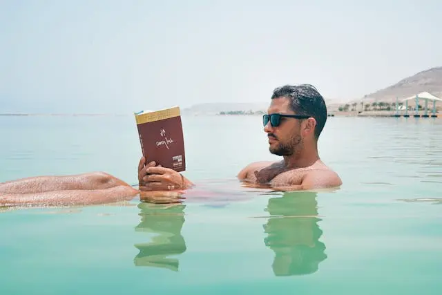 A man floating in the Dead Sea reading a book.