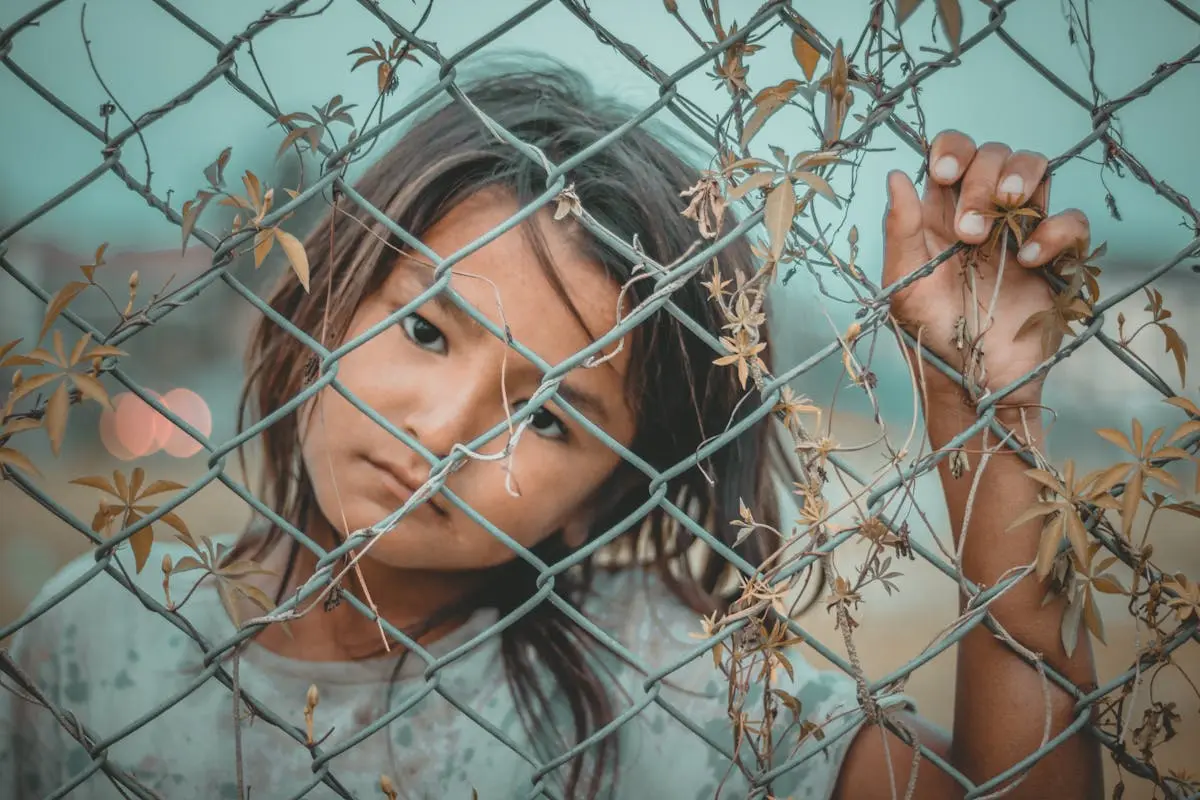 A child looking through a fence. Do you have children or hope to one day have children? Take a look at our recent article and learn what it means to be a parent.