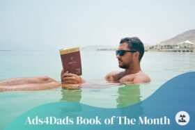 A man floating in the sea while reading one of our amazing books of the month from Ads4dads.com